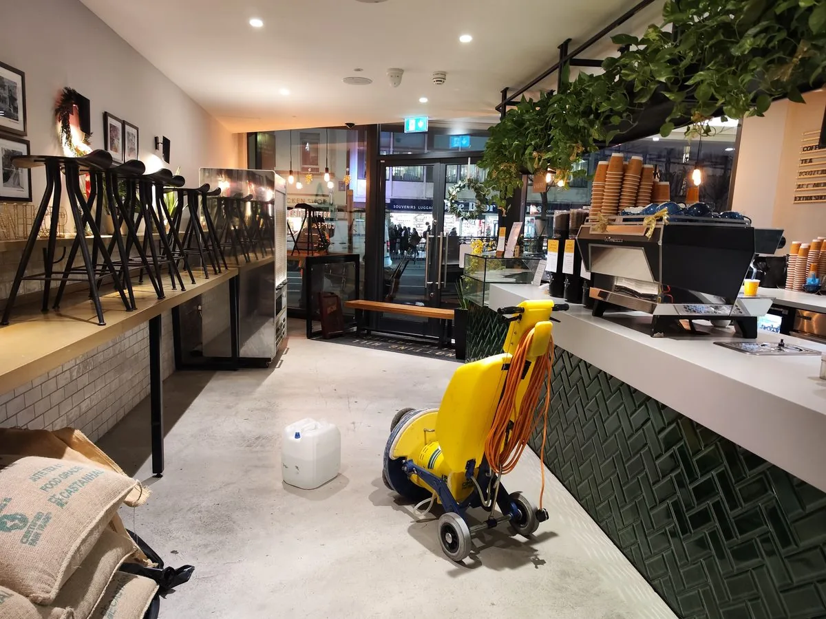 Rotary floor machine cleaning a London café floor before opening