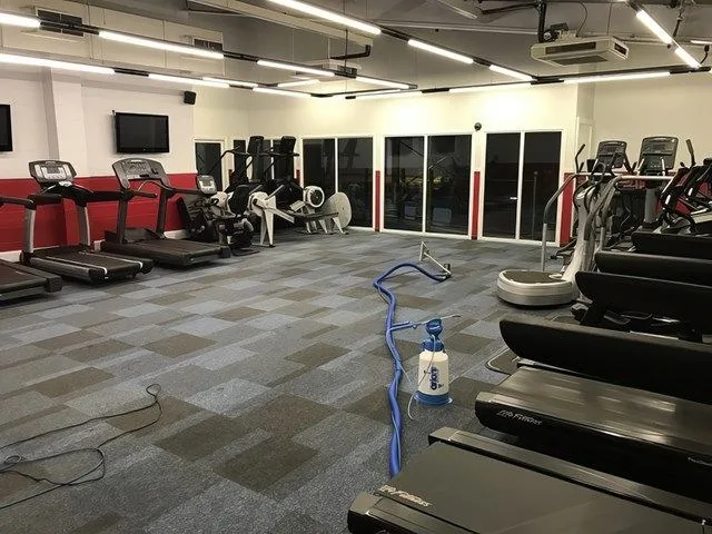 Gym floor carpet tiles being deep cleaned between treadmills
