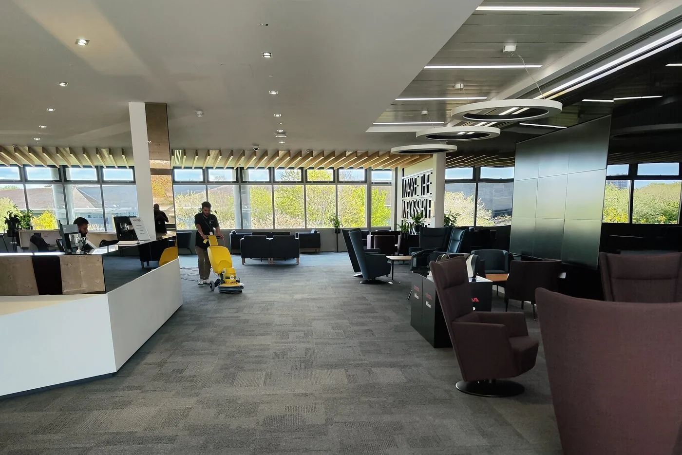 Capital Carpet Cleaners operative cleaning carpet tiles across an open-plan office floor and breakout lounge in London